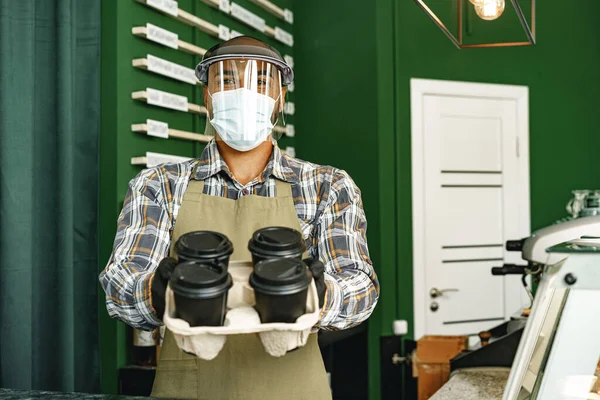 Trabajador de cafetería con máscara médica mientras está de pie en el mostrador en la cafetería —  Fotos de Stock