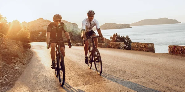 두 명의 전문 자전거 선수가 함께 아침에 자전거를 타고 달리는 모습 — 스톡 사진