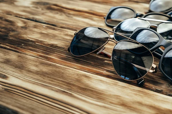 Set di occhiali da sole scuri su una superficie di legno marrone — Foto Stock