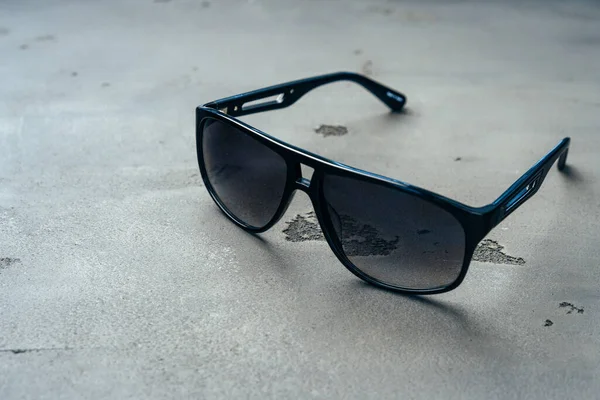 Dark male sunglasses on grey concrete surface — Stock Photo, Image