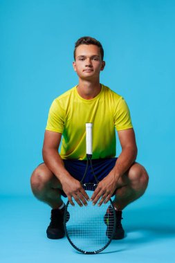 Mavi arka planda bir tenisçinin tam boy stüdyo portresi