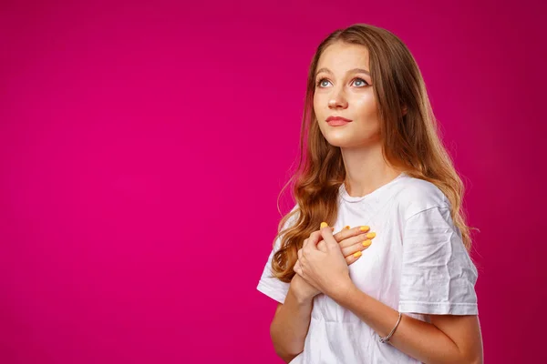 Jonge casual vrouw die handen op haar borst houdt en hopelijk omhoog kijkt — Stockfoto