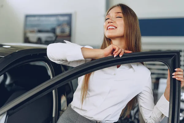 Красива молода жінка торкається своєї нової машини з задоволенням — стокове фото