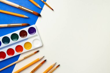 Suluboya boya kutusu ve mavi ve beyaz arka planda fırça seti