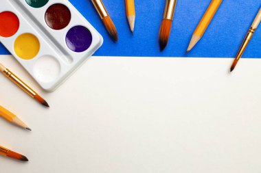 Suluboya boya kutusu ve mavi ve beyaz arka planda fırça seti