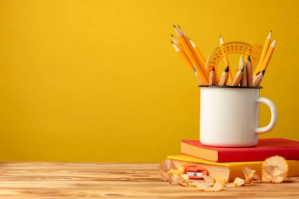 Metal cup with sharp pencils and pencil shavings on wooden desk — Stock Photo, Image