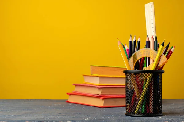 Copo de escritório com lápis e artigos de papelaria contra fundo amarelo — Fotografia de Stock