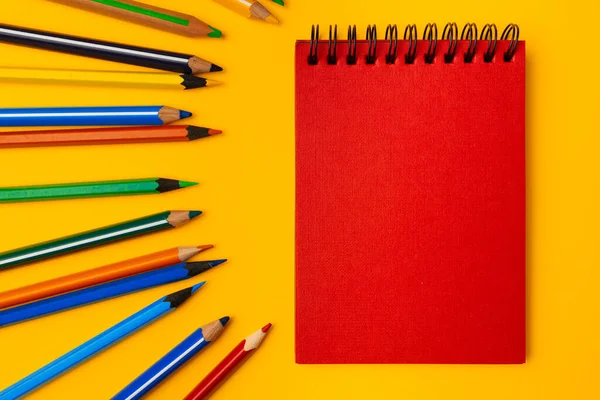 Блокнот і кольорові олівці на робочому просторі зверху — стокове фото