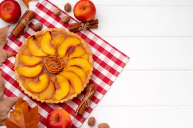 Kuru yapraklar ve tarçın çubuklarıyla süslenmiş beyaz tahta üzerinde sonbahar teşekkür pastası.