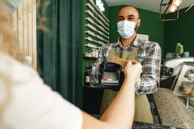 Kafede kredi kartıyla ödeme yapan kıvırcık kadın.