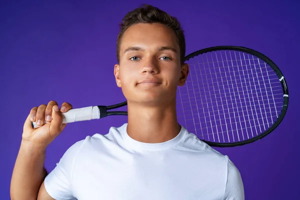 Jovem jogador de tênis branco posando com raquete de tênis contra fundo roxo — Fotografia de Stock