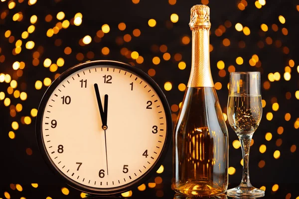 New Year eve concept with alarm clock against blurred garland