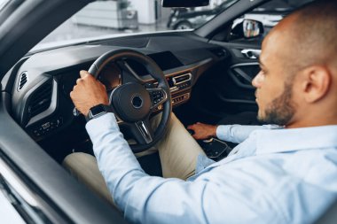 Yeni arabasında oturan yakışıklı, mutlu, Afro-Amerikan bir adamın portresi.