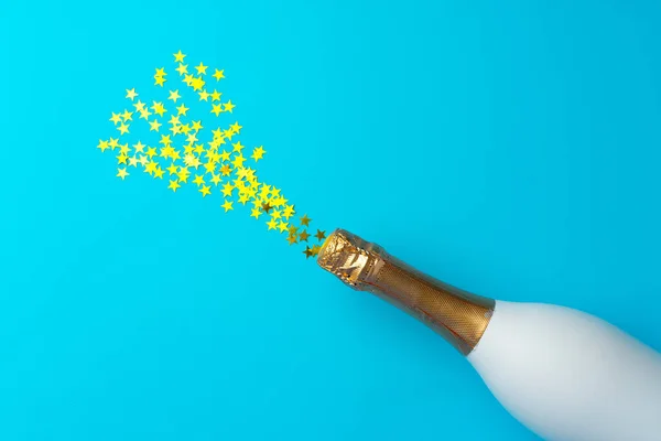 Champagne fles en confetti sterren op blauwe achtergrond plat lay — Stockfoto