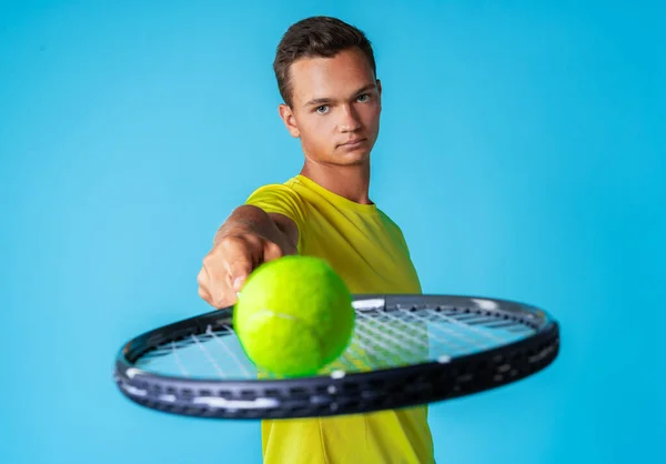 Young man tennis player in sportswear posing against blue background