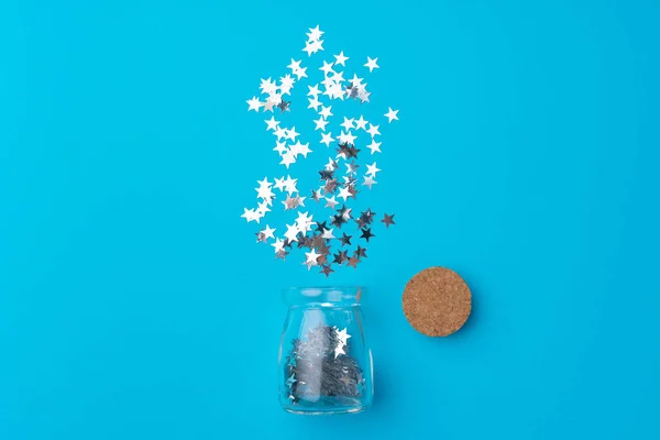 Glazen pot met verspreide confetti op blauwe achtergrond — Stockfoto