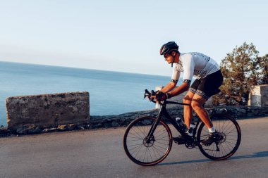 Bisikletli bir adam gün batımında açık havada bisiklet sürüyor.