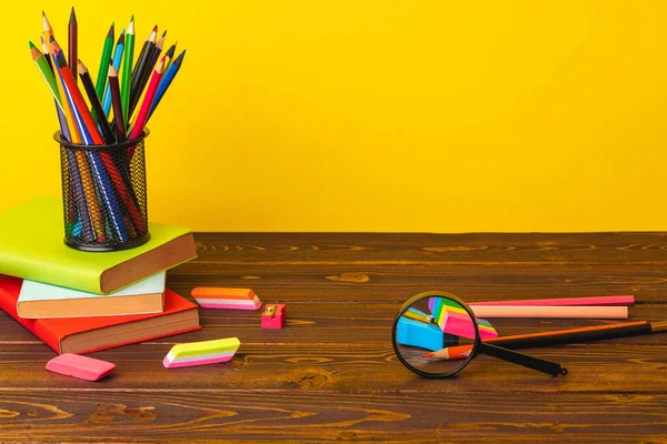 Чашка цветных карандашей и стопка книг — стоковое фото