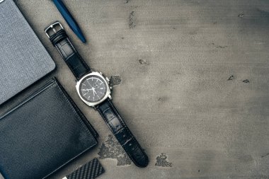 Koyu gri arka planda not defteri, saat ve çanta da dahil olmak üzere iş adamları aksesuarları