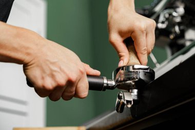Kadın kafe çalışanı kahve makinesinde kahve hazırlıyor.