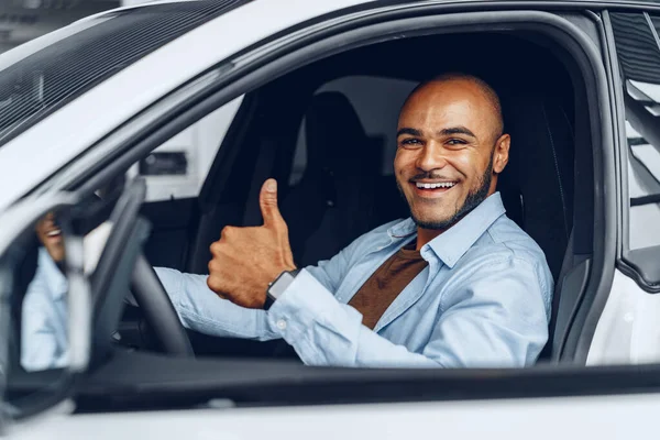 Retrato de un apuesto hombre afroamericano feliz sentado en su coche recién comprado — Foto de Stock