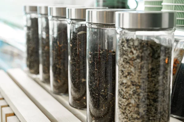 Glazen potten met droge theebladeren op de toonbank van een coffeeshop — Stockfoto