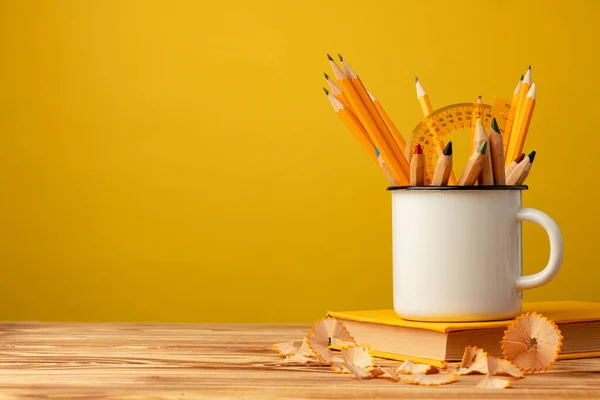 Металлическая чашка с острыми карандашами и стружками для карандашей на деревянном столе — стоковое фото
