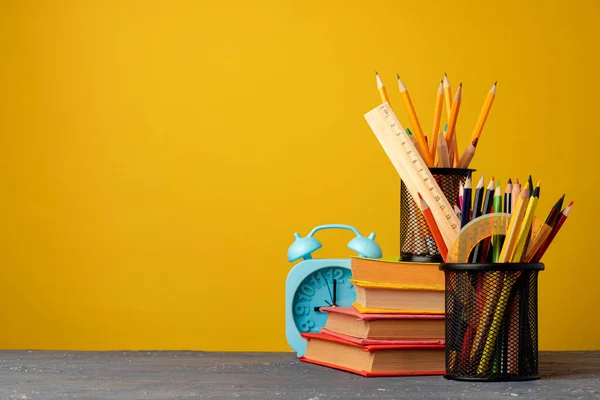 Copo de escritório com lápis e artigos de papelaria contra fundo amarelo — Fotografia de Stock