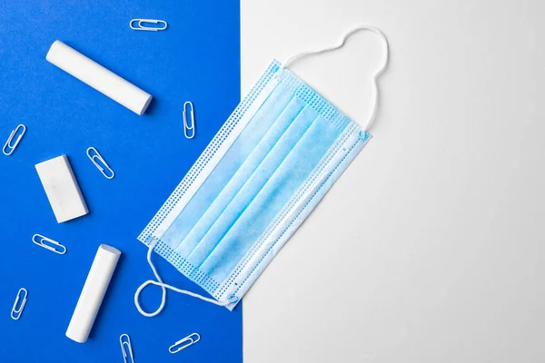 Pedaços de giz, clipes de papel e máscara médica sobre fundo azul e branco — Fotografia de Stock