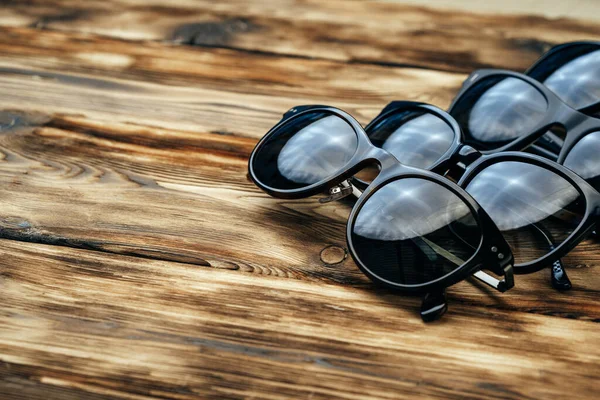 Συλλογή από σκούρα γυαλιά ηλίου σε καφέ ξύλινη επιφάνεια — Φωτογραφία Αρχείου
