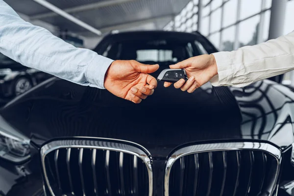 Araba satıcısı ve alıcısı araba galerisinde yeni bir arabaya karşı el sıkışıyor. — Stok fotoğraf