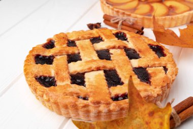 Kuru yapraklar ve tarçın çubuklarıyla süslenmiş beyaz tahta üzerinde sonbahar teşekkür pastası.