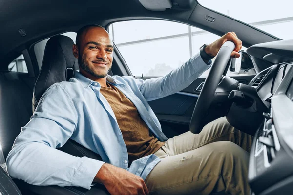 Retrato de un apuesto hombre afroamericano feliz sentado en su coche recién comprado — Foto de Stock