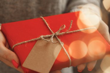 Süveter giymiş kadın elleri, paketlenmiş Noel hediyeleri.