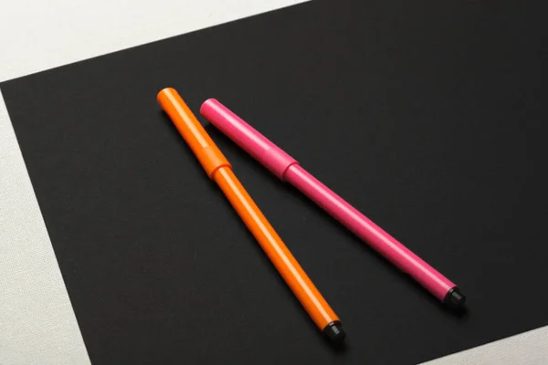 黒紙の背景にピンクとオレンジの二つのフェルトペン — ストック写真