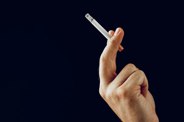 Mužská ruka s hořící cigaretou na černém pozadí — Stock fotografie