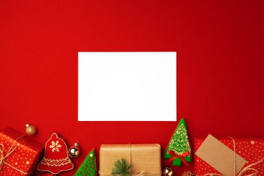 Noel hediyeli boş bir kağıt ve kırmızı arka planda zencefilli kurabiye.