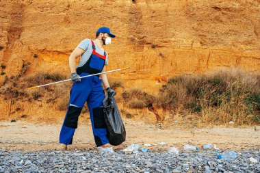 Kumsalda çöp toplayan gönüllü bir adam.