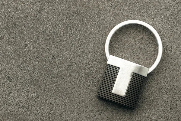 Koyu beton arkaplanda metal anahtar kolyesi — Stok fotoğraf