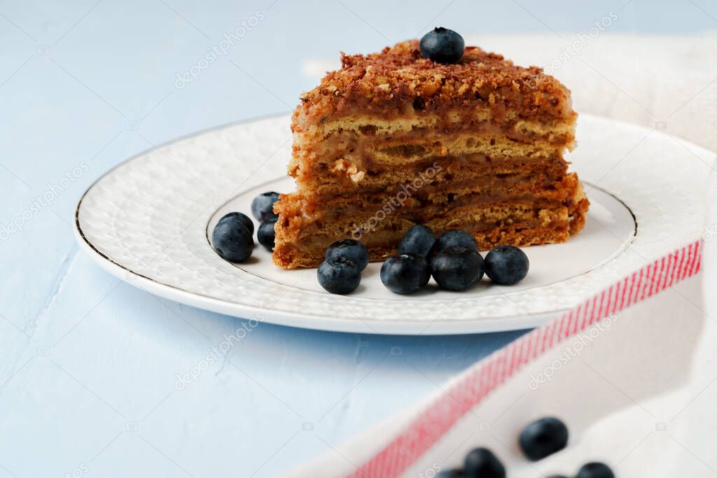 Piece of honey cake with nuts on white plate