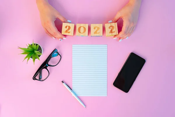 Kobiece ręce i otwarty notatnik na różowym tle — Zdjęcie stockowe