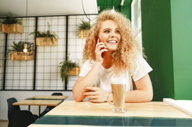 Kafeteryada genç ve güzel bir kadın telefonda konuşuyor.