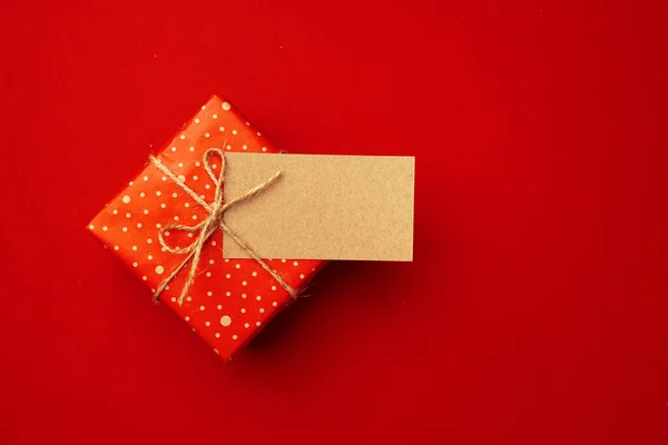 Blank sheet of paper and wrapped present for Christmas celebration on red background — Stock Photo, Image