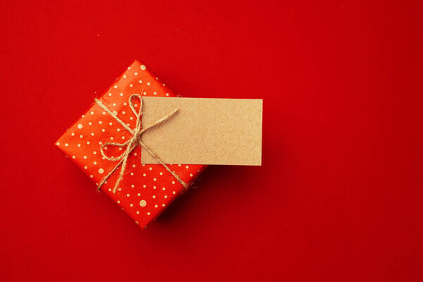 Blank sheet of paper and wrapped present for Christmas celebration on red background