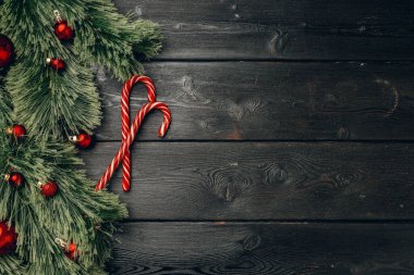 Kara tahta üzerinde kozalaklı dallar ve baston şekerler.