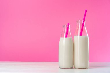 Pembe arka planda iki bardak süt ya da milkshake.