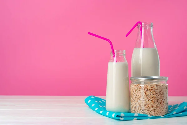 Дві скляні пляшки молока або молочного коктейлю на рожевому фоні — стокове фото