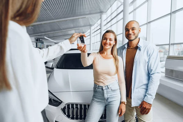 Vendedora de carros em uma concessionária de carros conversando com clientes — Fotografia de Stock