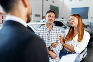 Erkek araba satıcısı yeni arabanın özelliklerini çifte anlatıyor.