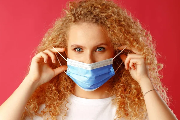 Beautiful young lady with curly hair wearing medical face mask